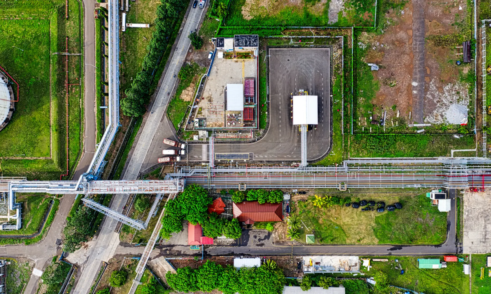 Luchtfoto van een bedrijfsterrein met wegen, groen en installaties